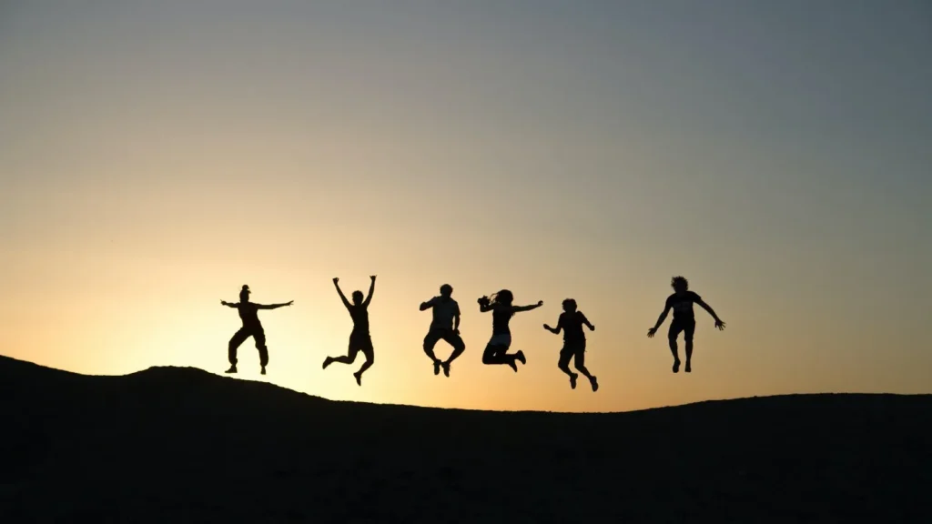 sillhouettes of people jumping for joy in front of a sunset