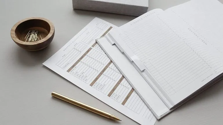 expense sheets, notebook, paperclips, and pen
